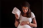 Unhappy pregnant woman with food coupons over black background