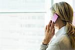 Woman using cell phone, looking out window