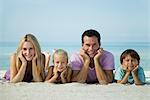 Familie liegend auf Sand am Strand, Porträt