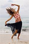 Woman dancing and tossing hair on beach