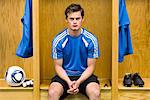 Young soccer player sitting in locker room, portrait