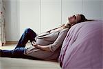 Pregnant woman leaning against bed resting