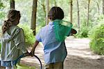 Children walking in woods together with butterfly net and bucket