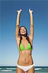 Woman in bikini stretching at the beach