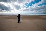 Toddler walking on beach, rear view