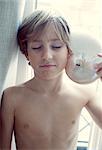 Boy holding seashell to ear with eyes closed, portrait