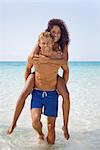 Paar am Strand, Mann mit Frau auf dem Rücken