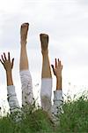 Mädchen mit Armen und Beinen in die Luft angehoben auf Rücken in hohem Gras liegend