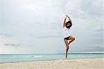 Young woman jumping in air on beach