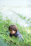 Boy looking at vegetation through magnifying glass