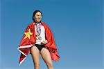 Sportlerin auf Podium des Siegers, eingewickelt in chinesische Flagge