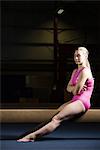 Female gymnast sitting on balance beam