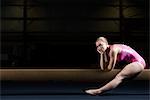 Gymnaste féminine assis sur une poutre d'équilibre