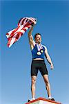 Male athlete on winner's podium, holding up American flag