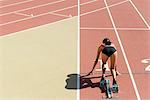 Woman crouched in starting position on running track, rear view