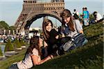 France, Paris, Three young women on lawn in front of Eiffel Tower