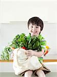 USA, Utah, Portrait of smiling boy (4-5) holding bag of vegetable