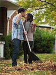 USA, Utah, Provo, Young couple kissing, raking leaves in garden