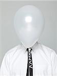 Studio portrait of young man wearing shirt and tie with face covered by white balloon