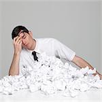 Studio portrait of young man behind stack of paper balls