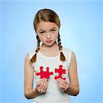 Studio portrait of girl (10-11) holding red jigsaw puzzles