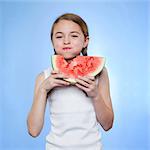 Studio shot of girl (10-11) eating watermelon