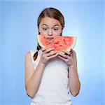 Studio shot of girl (10-11) holding slice of watermelon