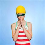 Studio shot of girl (10-11) wearing swimsuit, swimming cap and swimming goggles