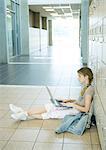 High school girl using laptop in school hallway