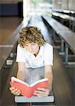 Teen boy reading book on bleachers