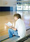 Teen Boy reading Buch auf Tribüne