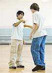 Two teen boys performing special handshake in school gym
