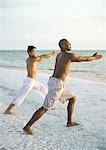 Two men doing relaxation exercise on beach