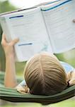 Jeune fille lisant livre d'école sur le hamac