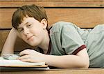 Boy lying on bench with homework