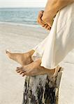 Mann sitzt am Strand mit den Füßen auf Holzpfosten, niedrig, Abschnitt