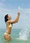 Frau stehend im Meer, Spritzwasser mit Händen