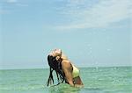 Woman standing in sea, head back and drops of water in air after flipping wet hair
