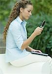 Junge Frau sitzt auf dem Stuhl, Arm Handy Nachrichten überprüfen