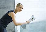 Woman leaning against glass guard rail, reading newspaper