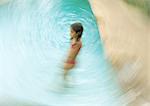 Girl standing in swimming pool, blurred motion