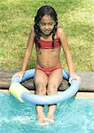 Girl sitting on edge of swimming pool
