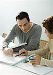 Man helping teenage son with homework