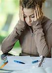 Preteen girl doing homework, holding head