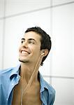 Young man listening to earphones, smiling