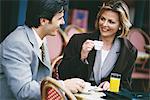 Businessman and woman sitting at sidewalk cafe, having coffee