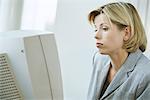 Businesswoman using desktop computer, frowning