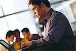 Young man using laptop, side view