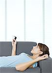 Junge Frau liegend auf Couch, MP3-Player anhören