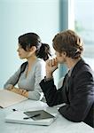 Mature man and teenage girl sitting at table, looking out of frame